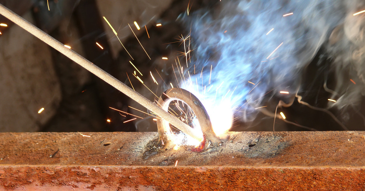 A skilled welder working on a metal fabrication, wearing protective gear and joining metal pieces together.