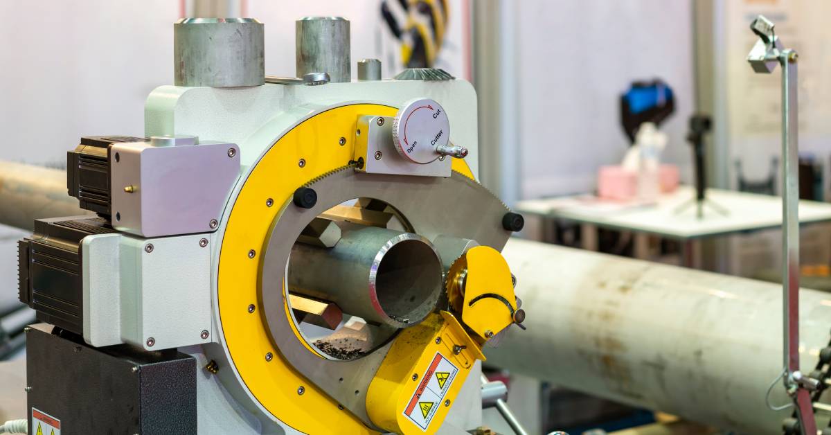 A beveled pipe resting inside a stationary cutter with a yellow cutting head positioned near the pipe’s edge.